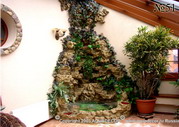 Зимний сад в мансардном этаже загородного дома оформлен с использованием декоративного водопада.